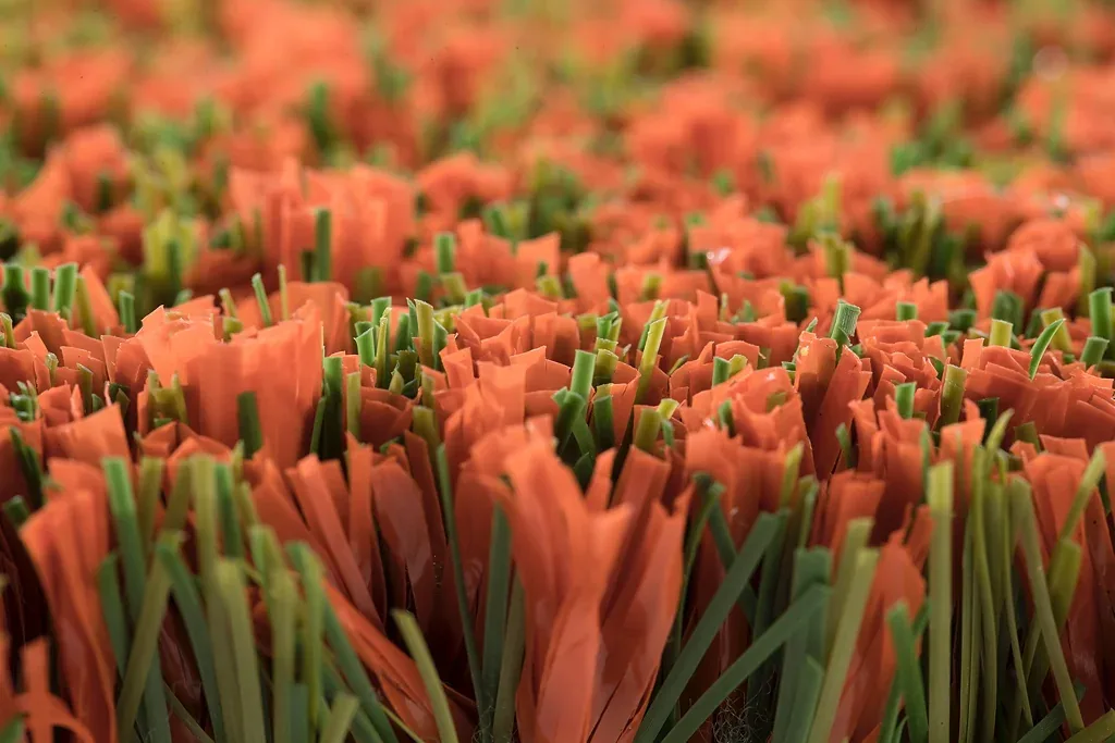 Close up of orange and green synthetic turf fibers built with Pointcarre YarnMaker, showing the blade profile